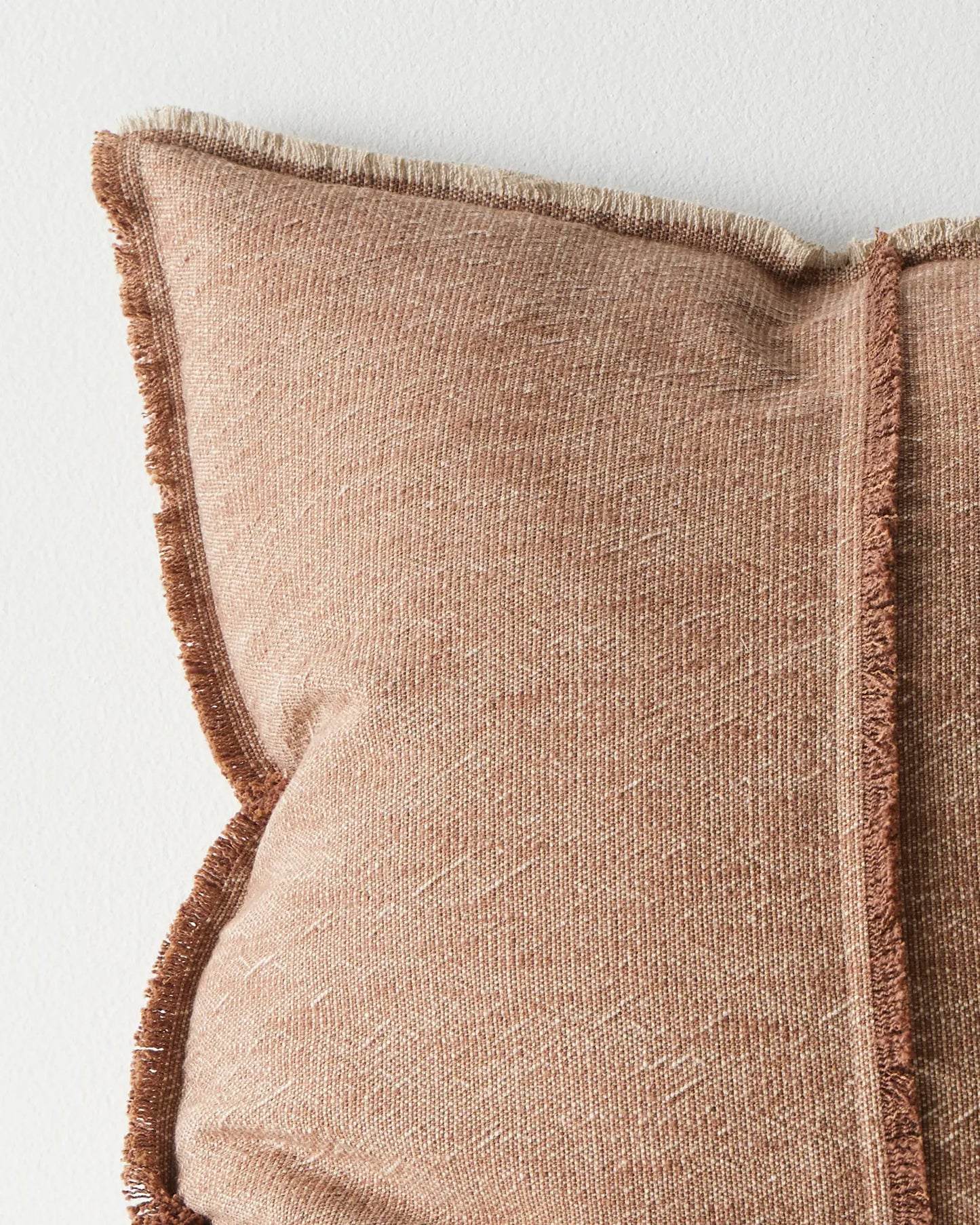 Close-up of a brown textured pillow with frayed edges on a light background
