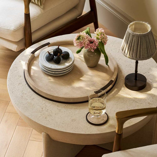 Round stone coffee table with decorative shagreen items in a living room setting
