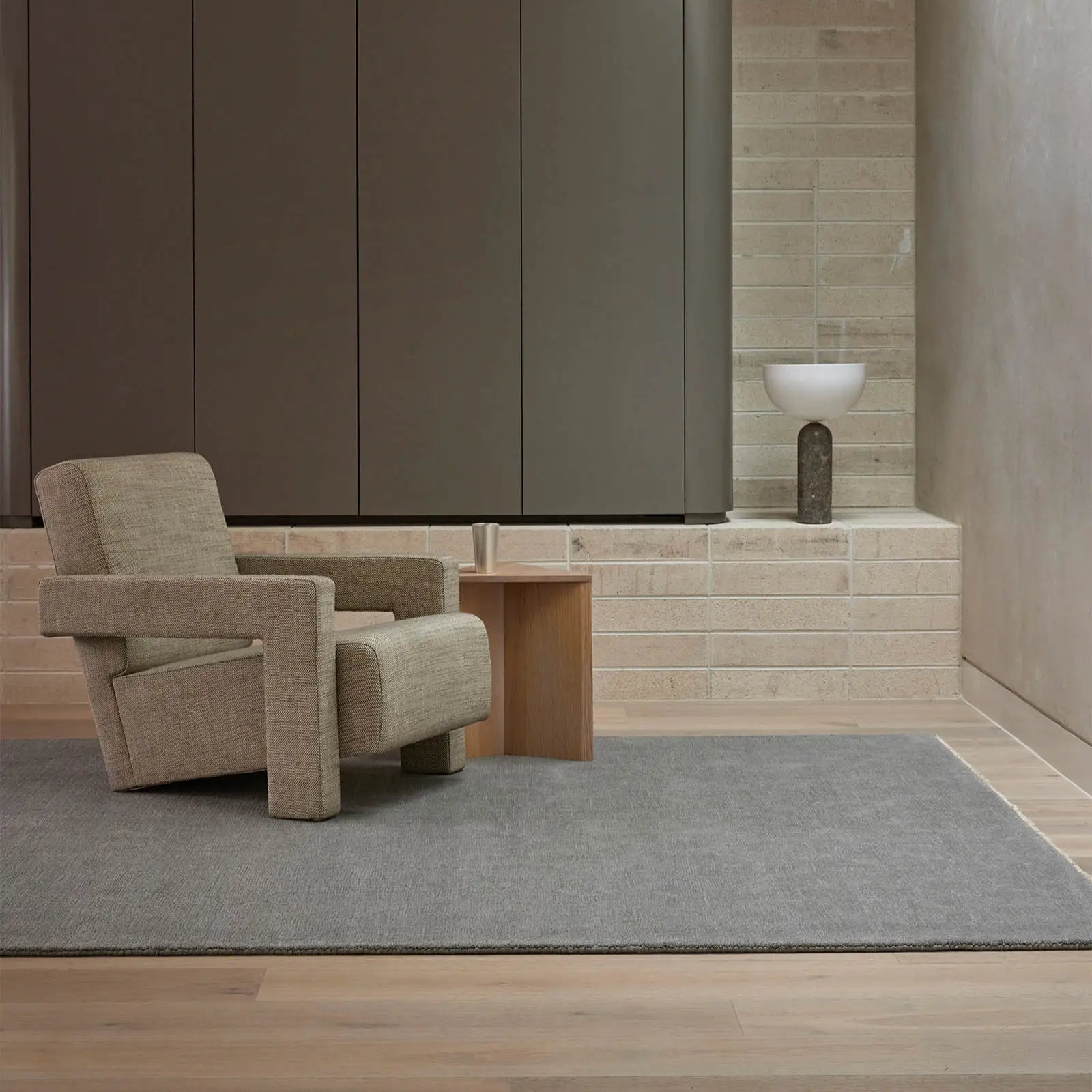 Alessandre rug in blue grey with a modern beige architectural chair on it