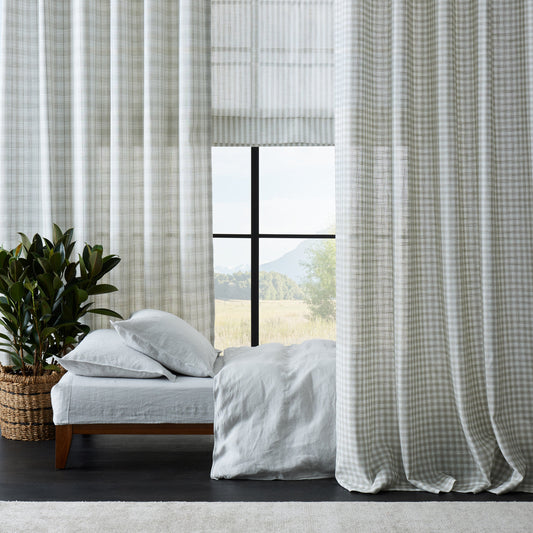 Bedroom with checkered curtains, bed, and plant