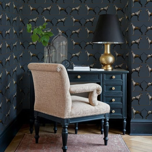 Chair in front of a desk with a lamp against a wall with dog patterned wallpaper