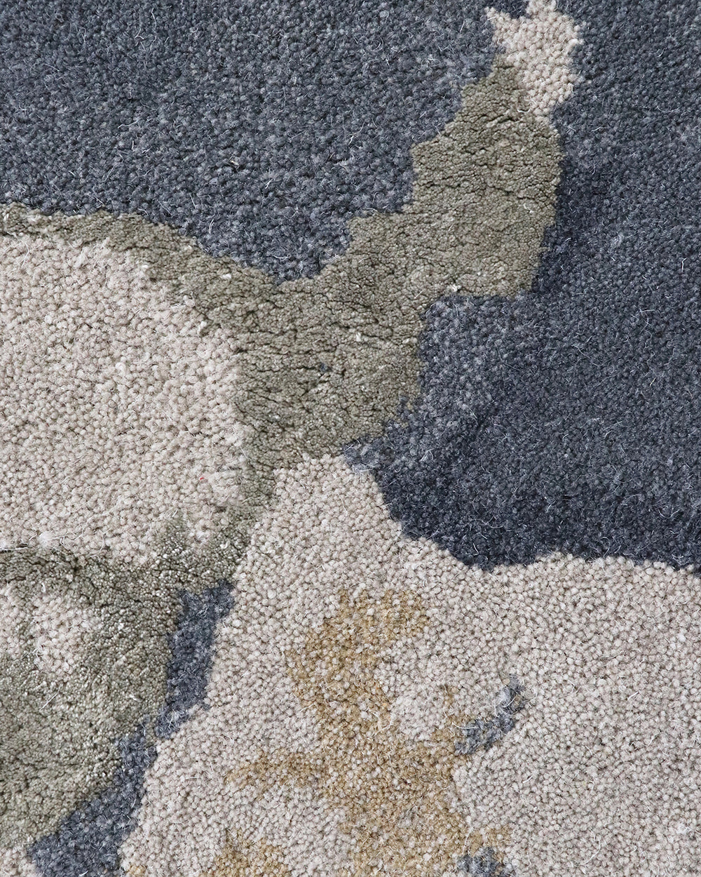 Close-up of a textured carpet with a geometric pattern in shades of gray, green, and beige.