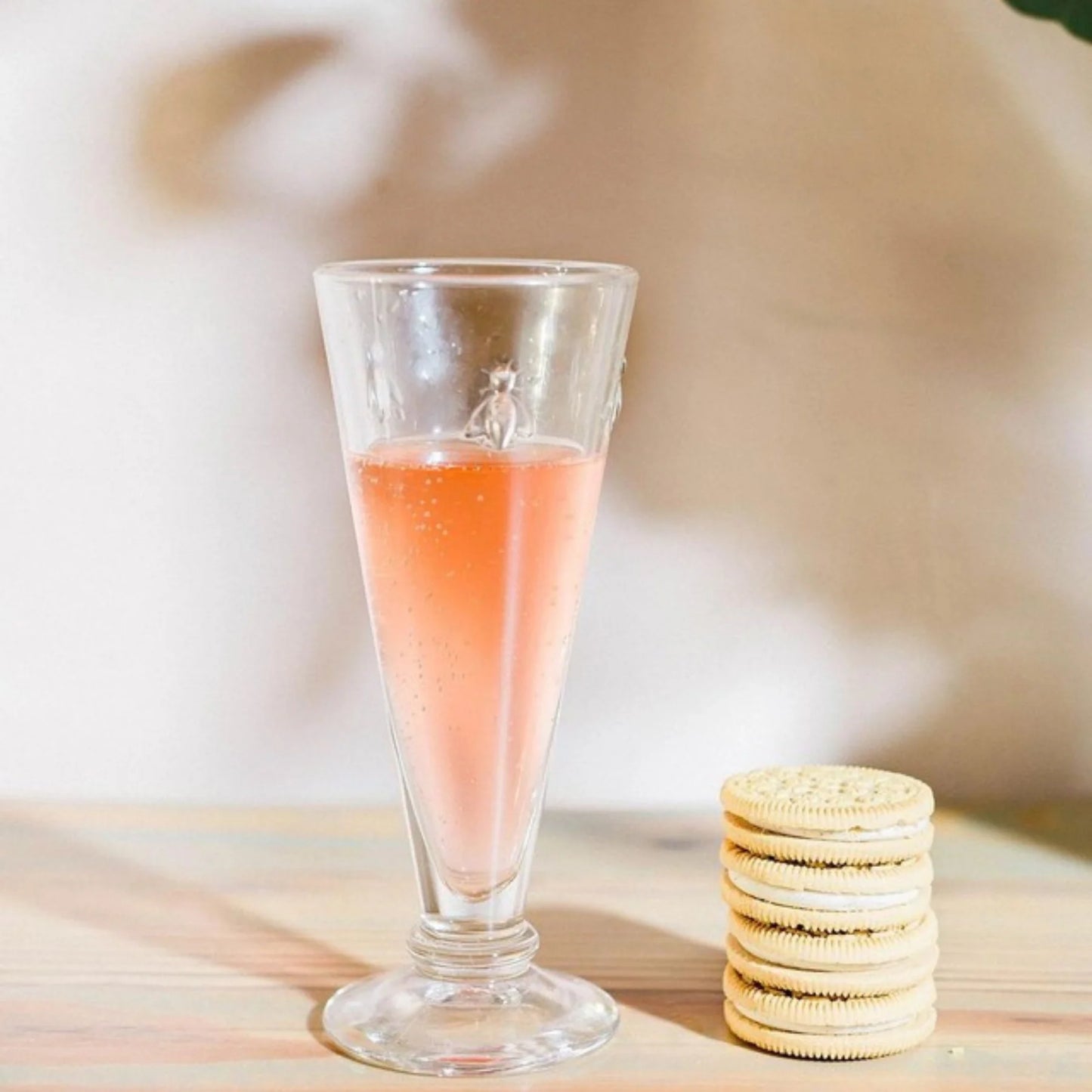 Glass of pink drink with a stack of cookies on a wooden surface