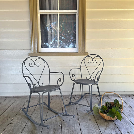Two metal chairs on a wooden deck with a window in the background.