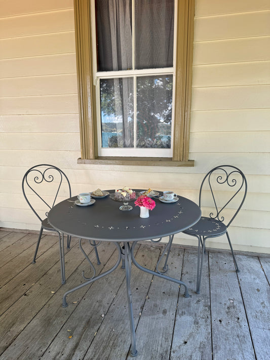 Outdoor patio set with a round table and two chairs on a wooden deck.