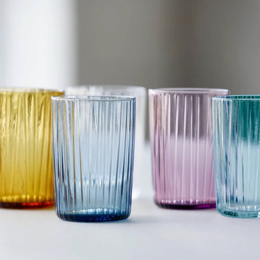 Set of colorful glass tumblers on a white surface with a neutral background
