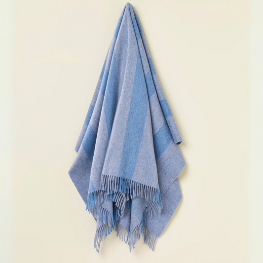 Blue striped merino throw blanket with fringe on a beige background