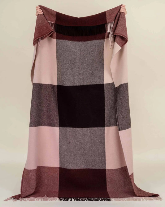 Plaid blanket with brown, pink, and gray colors on a beige background