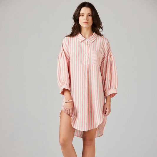 Woman wearing a pink striped nightshirt on a plain background