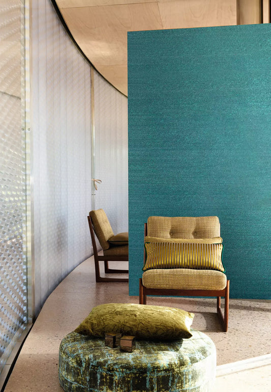 Modern interior with a green upholstered chair and ottoman against a teal wall.