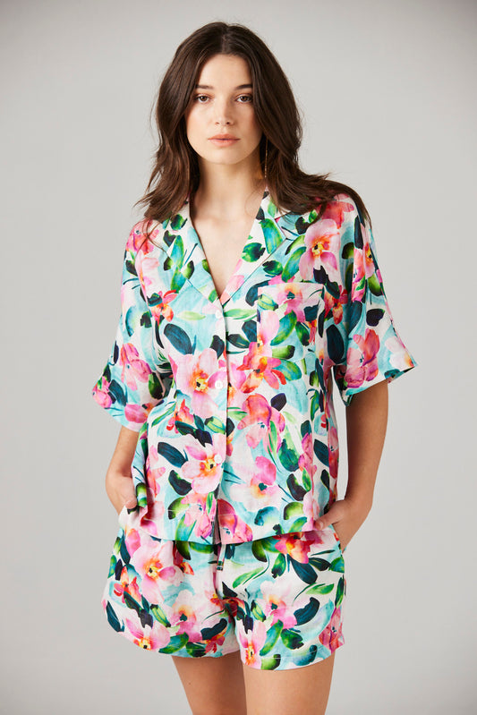 Woman wearing a colorful floral pajama set against a plain background