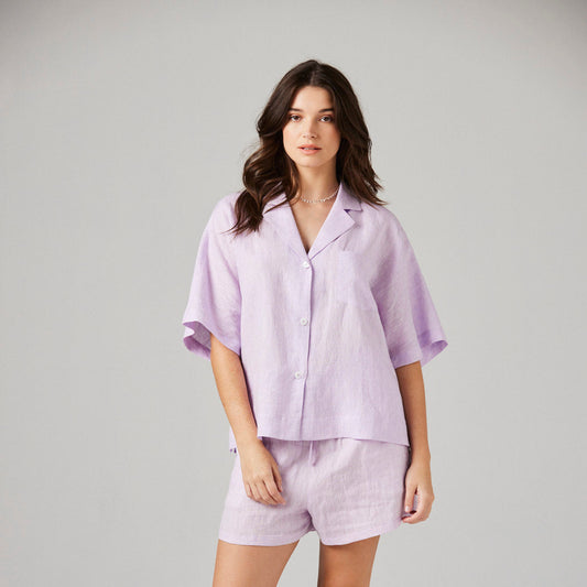 Woman wearing a lilac pajama set on a plain background