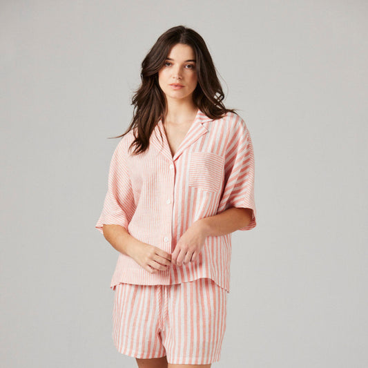 Woman wearing a pink pajama set on a gray background