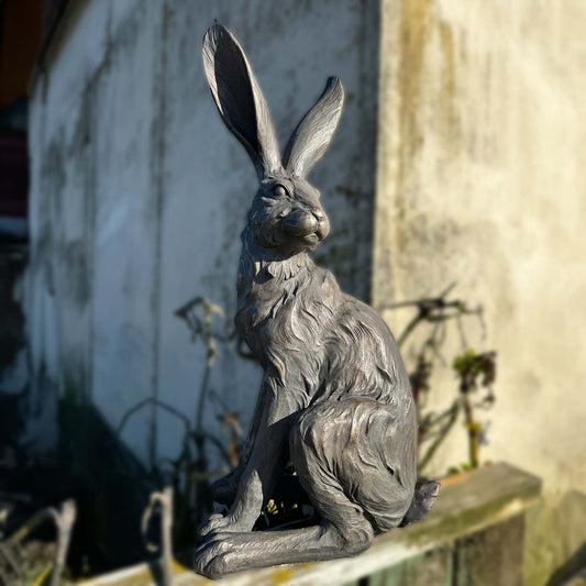 A statue of a country hare sitting on its hind legs in a silver grey with champagne highlights
