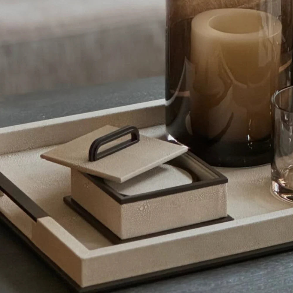 Decorative box with a lid on a tray next to a candle and glass.