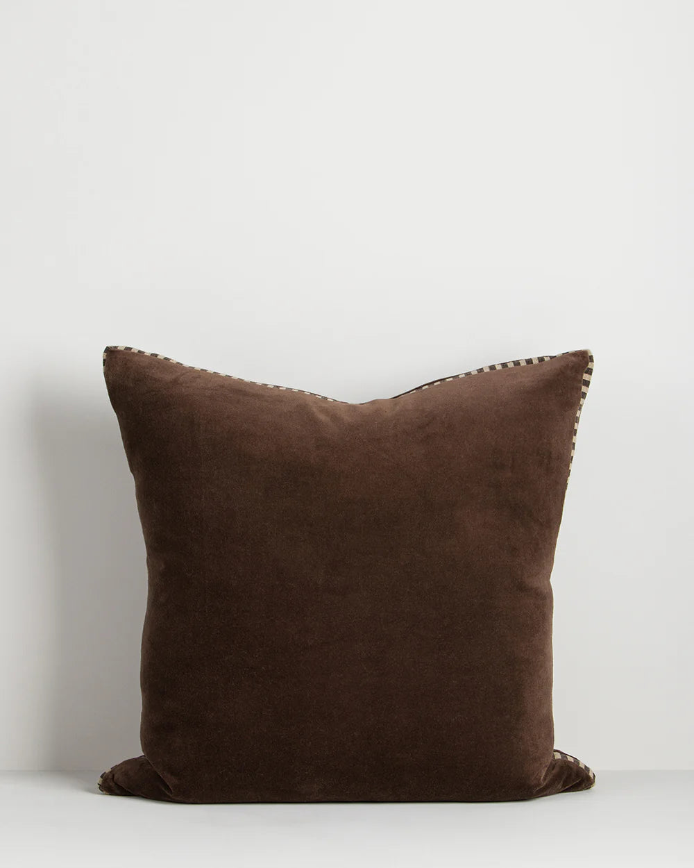 Brown pillow with decorative trim on a white background