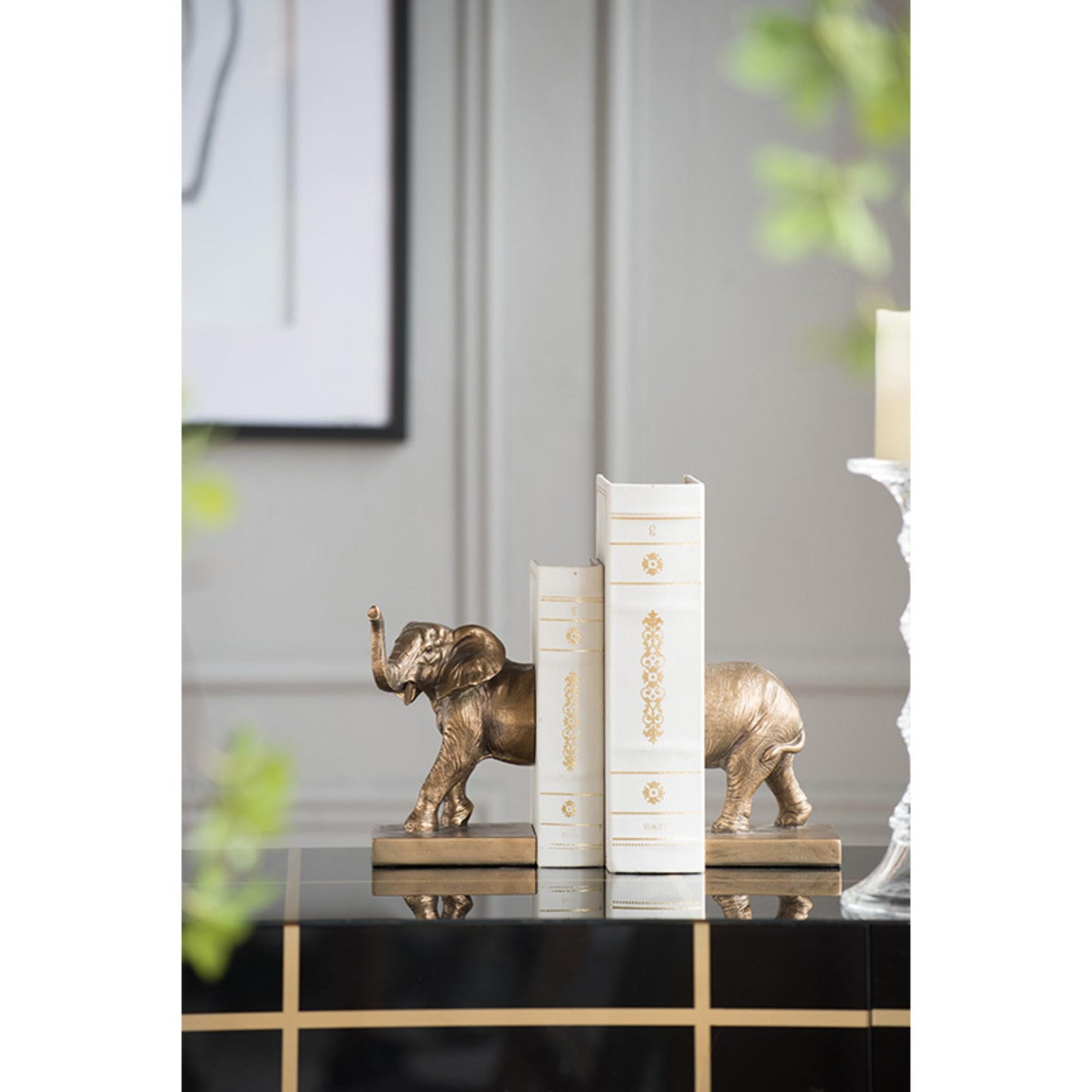 Bronze elephant figurines on books with a neutral background