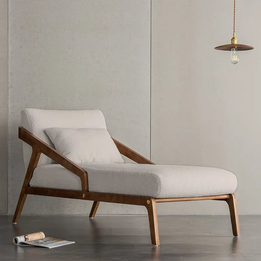 Modern chaise with wooden frame and white cushion in a minimalistic room.