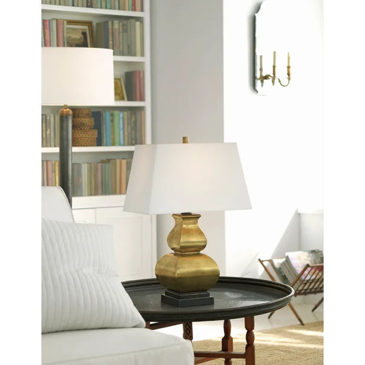 Fang Gourd gold tamp lamp on a wooden side table by Chapman and Myers