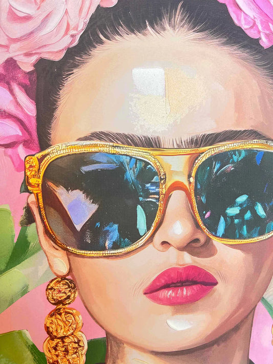 Close-up of Frida Kahlo wearing gold sunglasses with a colorful reflection, surrounded by pink flowers and green leaves.