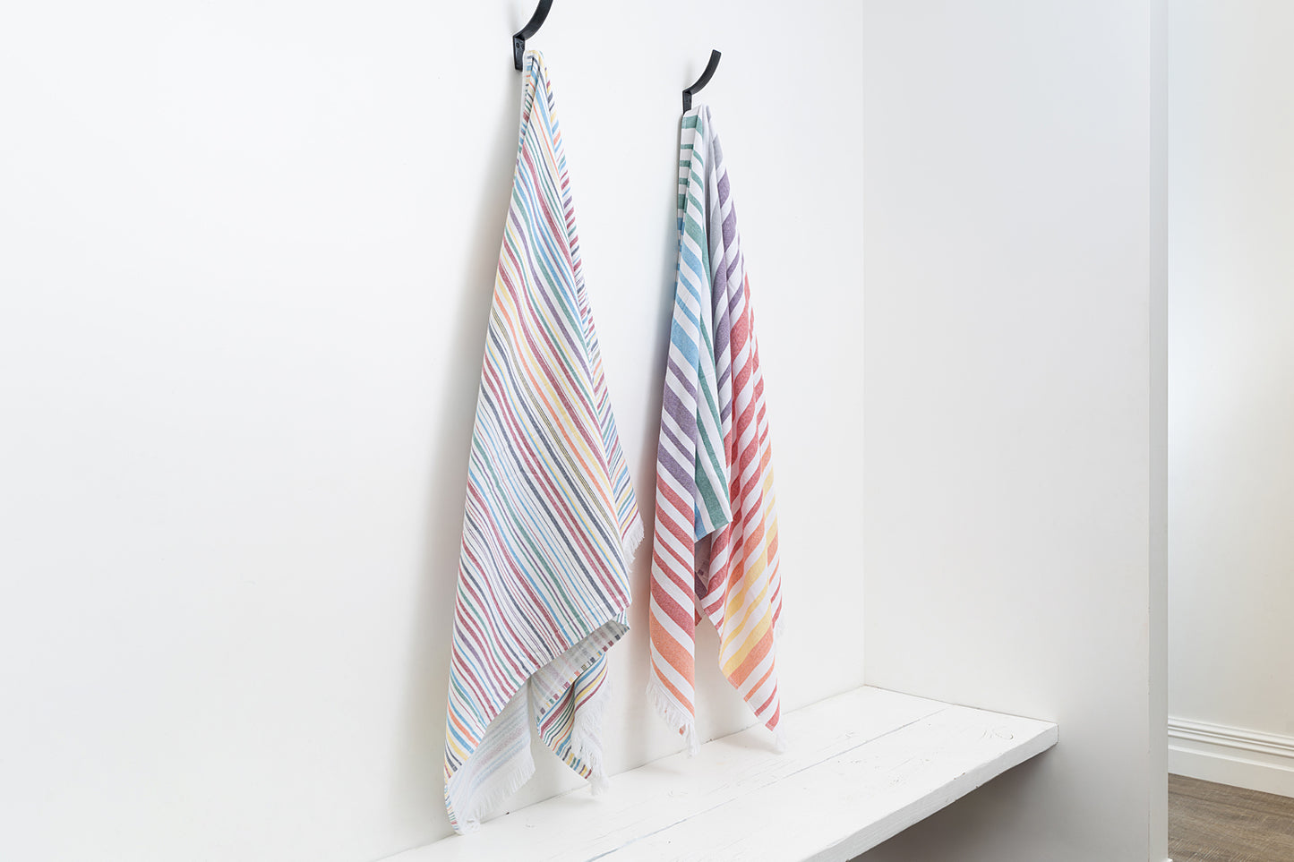 Two striped towels hanging on a rack against a white wall.