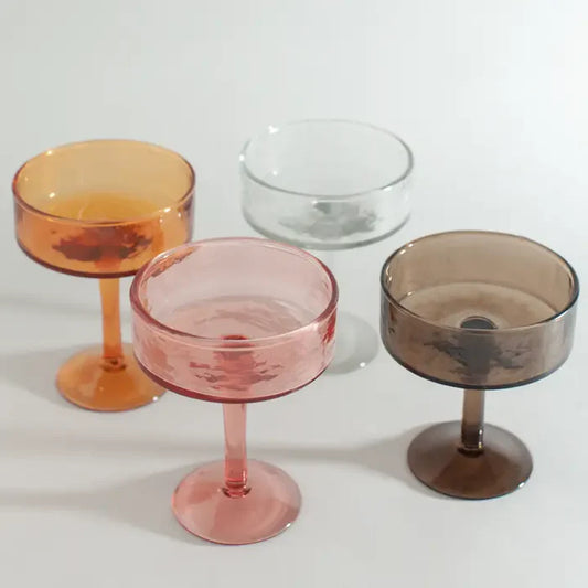 Four coupe cocktail glasses items with different colored bodies on a white background