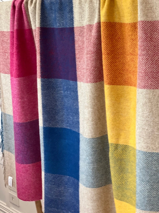 Colorful plaid fabric with a gradient of red, blue, yellow, and beige.