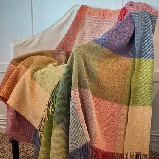 Colorful checkered blanket draped over a chair against a light blue wall.