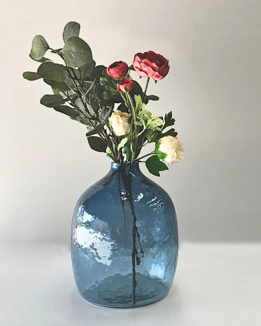 Blue glass vase with flowers on a white background