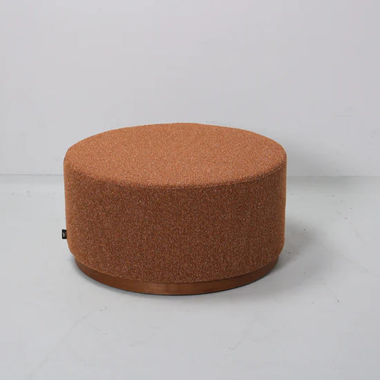 Round brown fabric ottoman on a light gray background