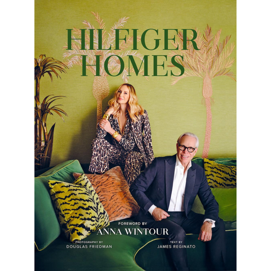 Book cover of 'Hilfiger Homes' with two people sitting on a couch against a green background with palm trees.