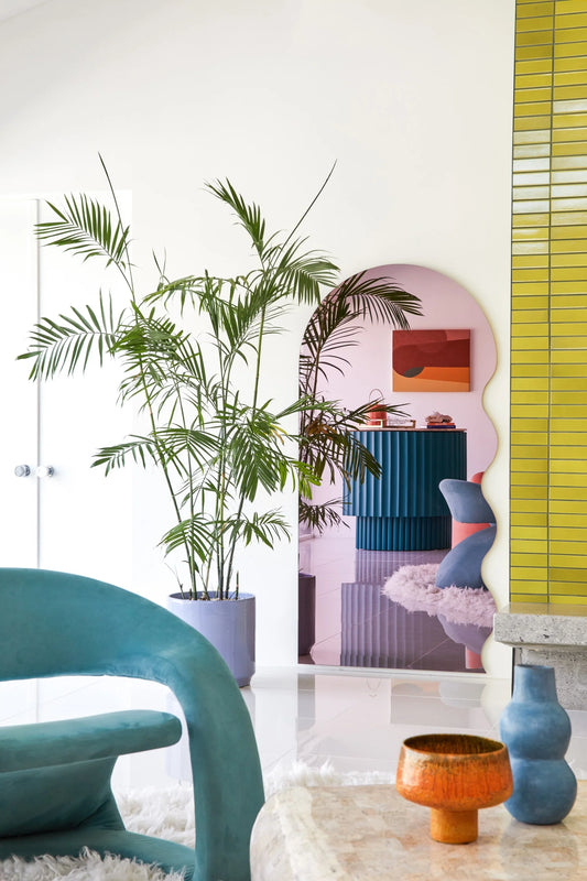 Modern interior with a blue chair, potted plant, and colorful wall art.