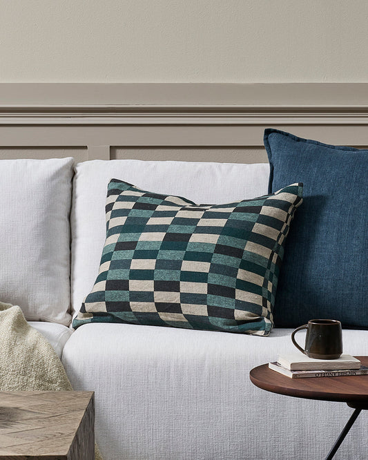 Gray sofa with checkered pillow and blue cushion against a neutral wall.