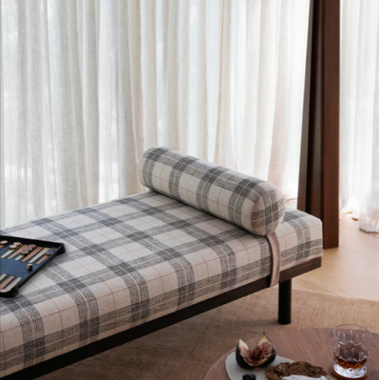 Plaid bed with a pillow and a lamp in a room with white curtains