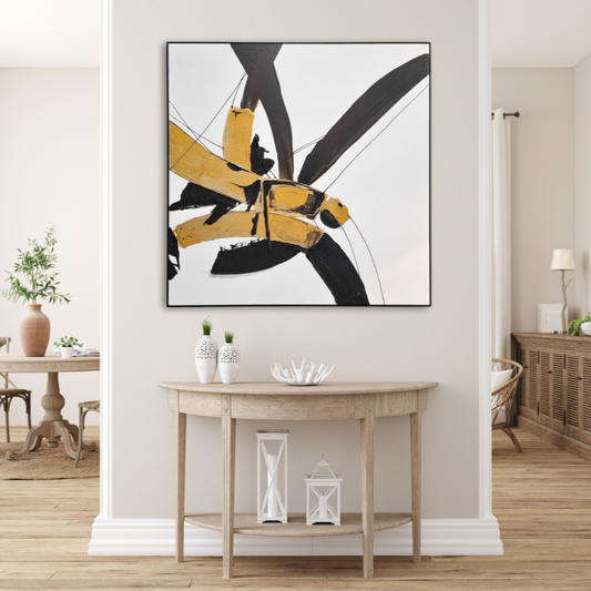 Kanji brush strokes in gold and black
on a large painting. Cream wall with light coloured wood furniture behind a wall in the background. Infront of the painting is a semi circular console table in light wood with white vases and objects on it.