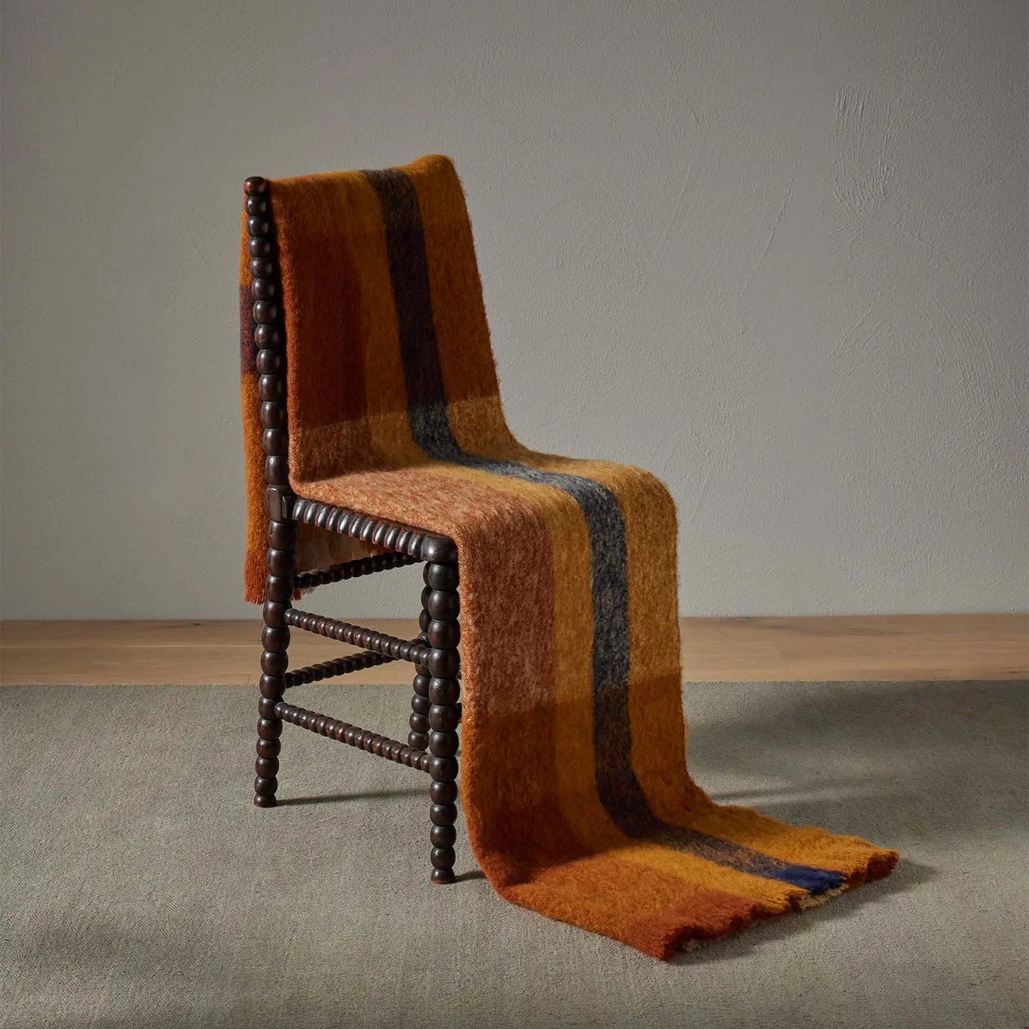 Kinloch throw draped over a chair in brown, cream russet and black check