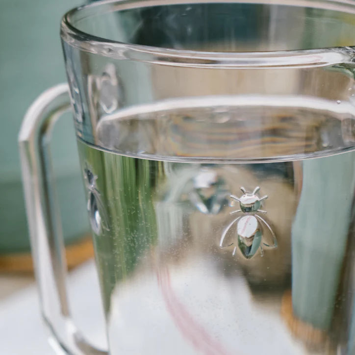 Clear glass mug with a decorative bee emblem on a blurred background