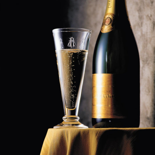 Bottle of champagne and a glass with bubbles on a dark background