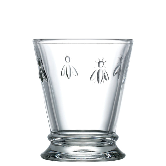 Clear glass tumbler with bee embossing on a white background