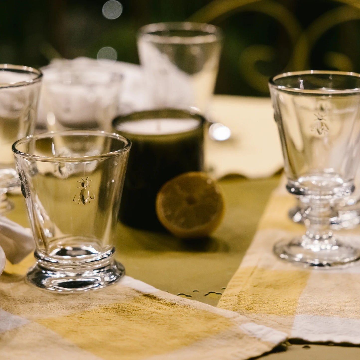 Clear glass shot glasses on a checkered tablecloth with a blurred background