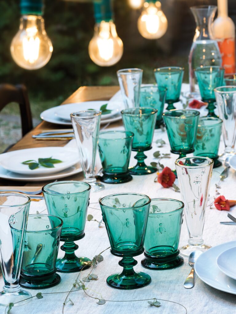 Table setting with teal glassware and white plates outdoors.