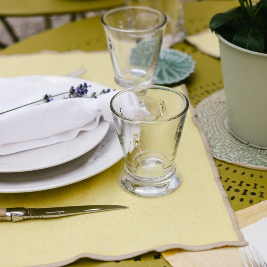 Table setting with plates, glasses, and cutlery on a yellow tablecloth.