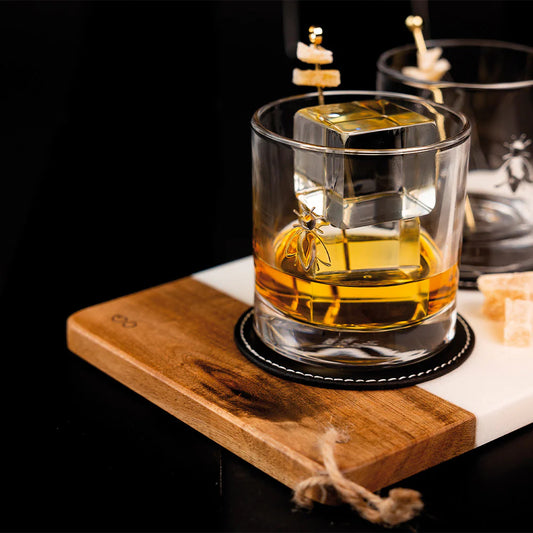 Glass of whiskey with a wooden coaster on a dark surface