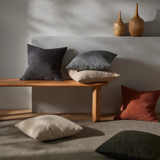 Laurent cushions in various colours scattered over a carpet and bench