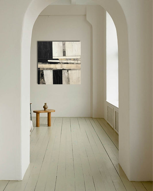 Minimalist interior with a wooden table and abstract painting in a room with arched doorways.