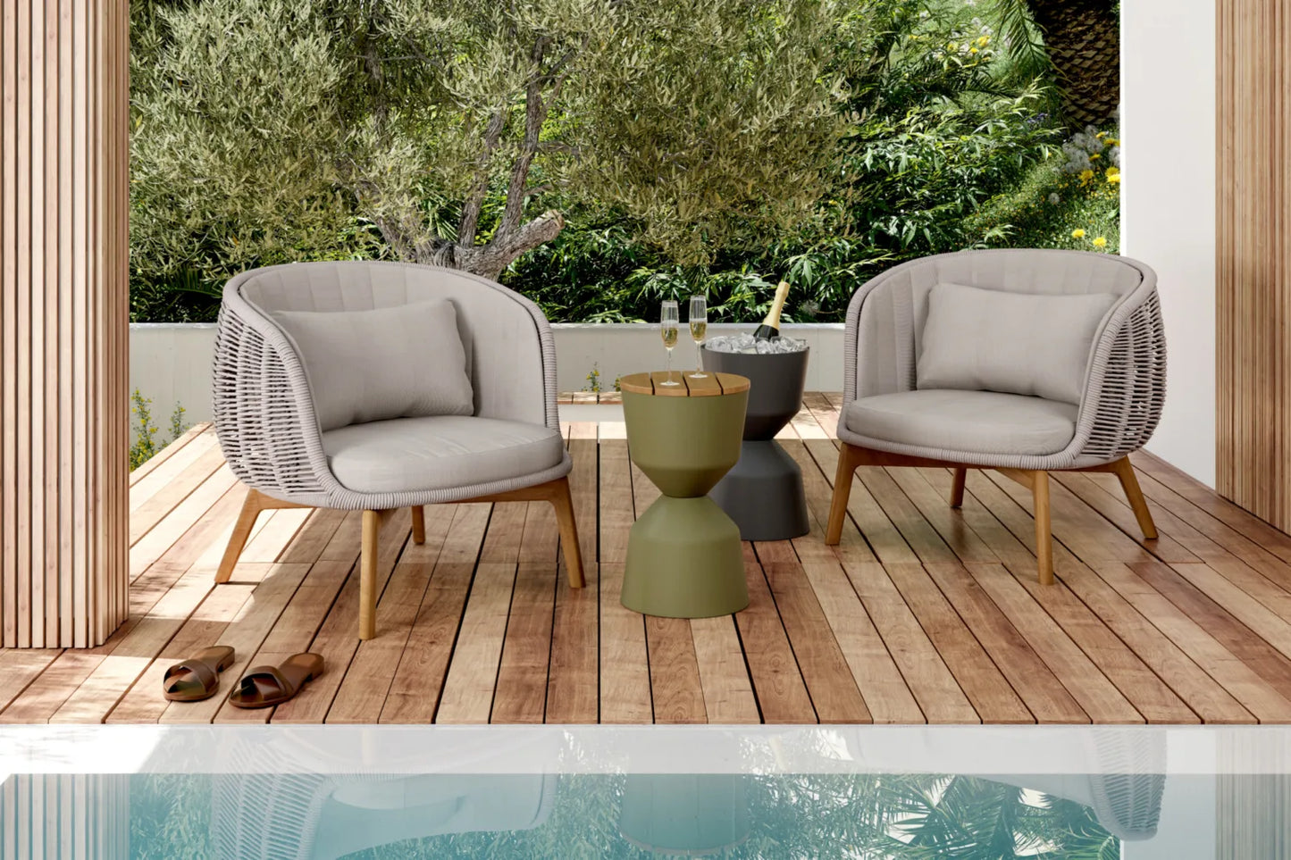 outdoor armchairs under on a wooden deck by a pool and greenery