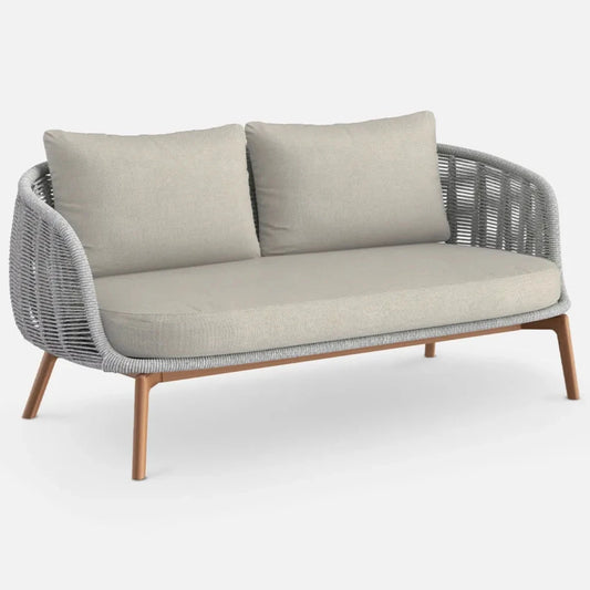 A modern outdoor sofa with double-woven pumice rope and teak effect aluminum legs, featuring soft taupe cushions.