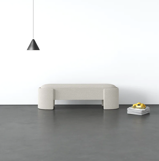 Modern beige sofa against a white wall with a black pendant light.