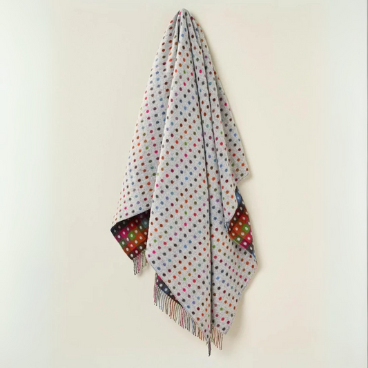 Polka dot throw
with fringes on a light grey background
