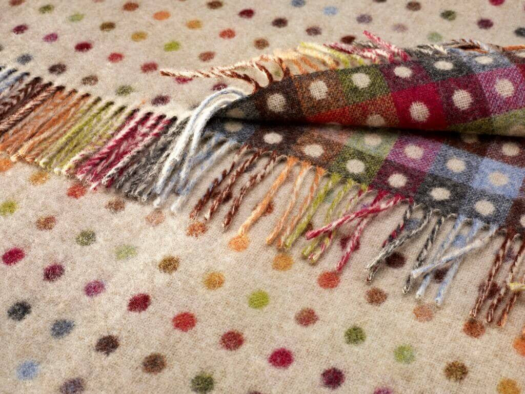 Multicolored patterned throw with fringes on a polka dot fabric background